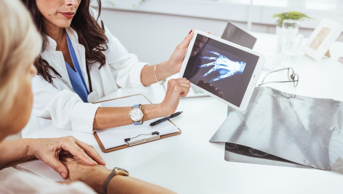 Young,Doctor,Examining,X Ray,Of,Hands,Of,A,Senior,Patient