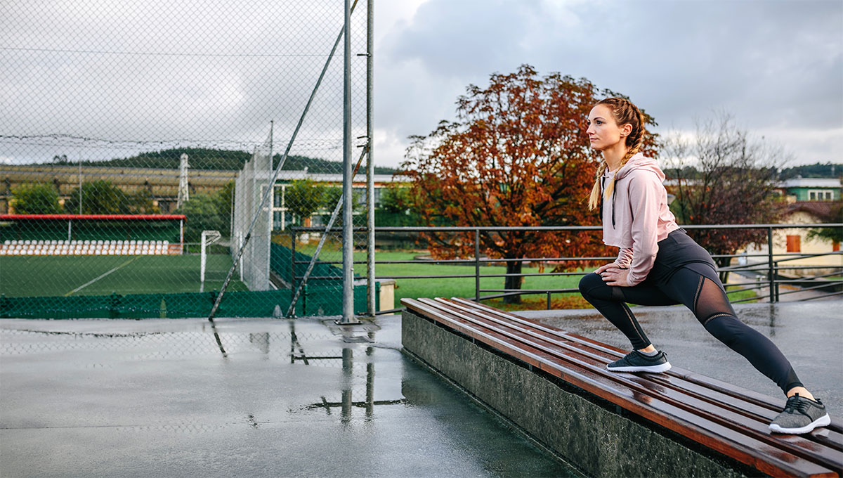 Young,Sportswoman,Stretching,Legs,On,A,Bench,Outdoors