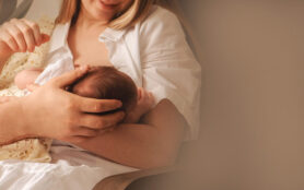 Young,Mother,Holding,And,Breastfeeding,Her,Newborn,Baby.,Father's,Hand